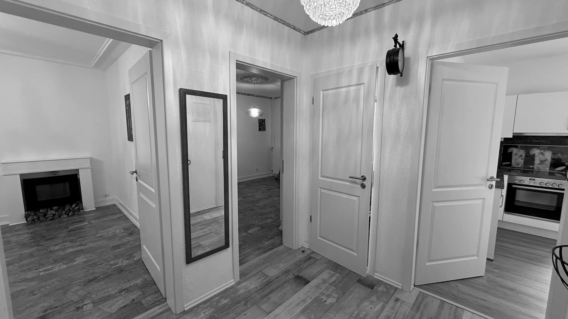 Sanierte Wohnung: heller Flur mit neuem Dielenboden, Blick in Wohnzimmer mit Cheminée und in die Küche